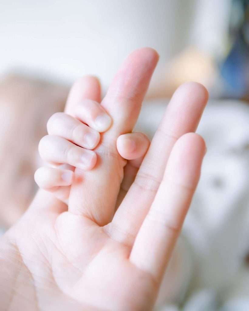 bebe sujetando tiernamente la mano de su pediatra